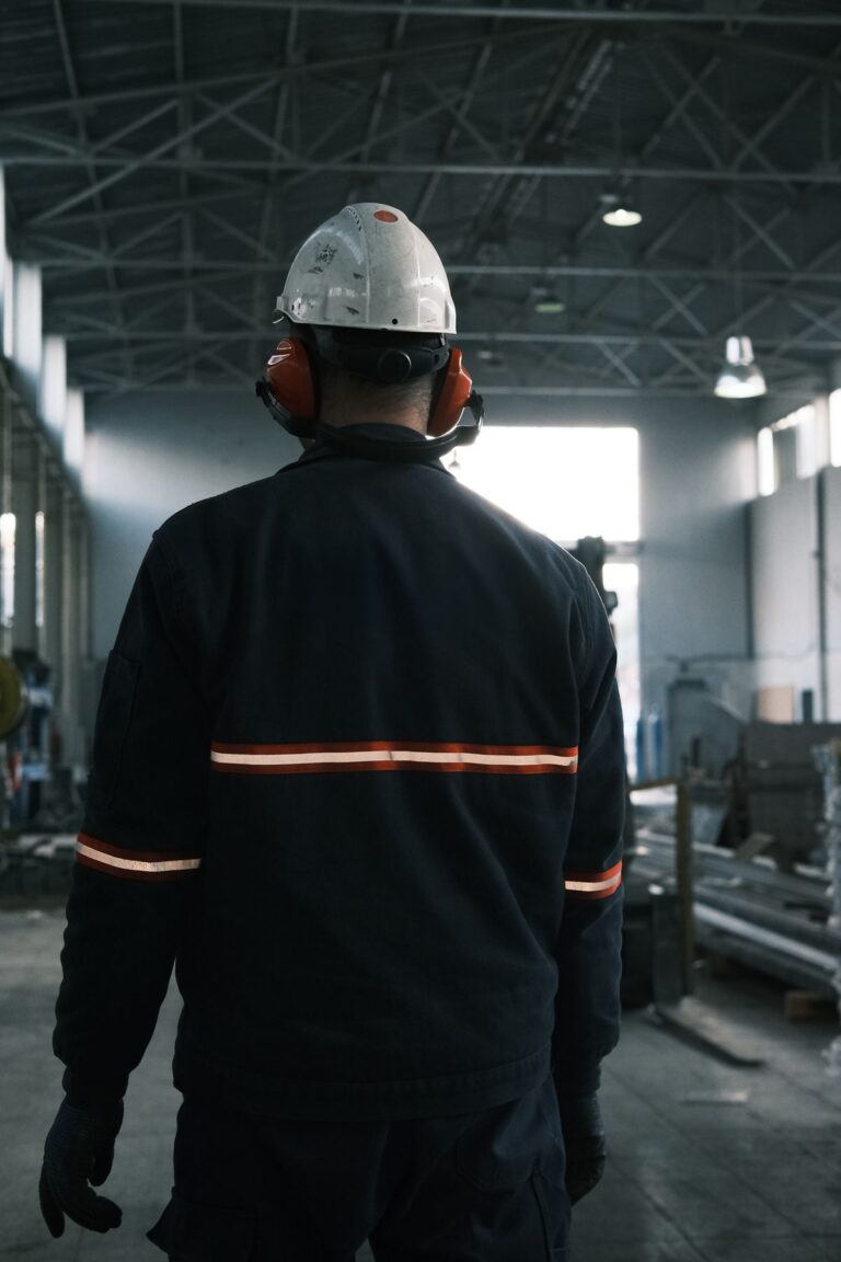 Operario com capacete e protetor auricular em ambiente industrial insalubre